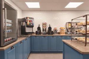 萨凡纳卡尔森萨凡纳市区乡村套房酒店的厨房配有蓝色橱柜和带面包的柜台。