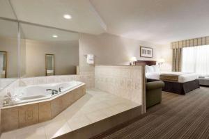 金斯兰金斯兰江山旅馆&套房酒店的带浴缸和床的酒店客房