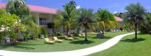 格兰德海滩雷迪森格林纳达海滩度假胜地的庭院里种有椅子和棕榈树的度假胜地