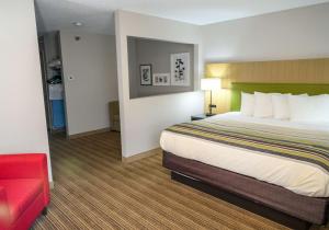 格林菲尔德Country Inn & Suites by Radisson, Greenfield, IN的酒店客房,配有一张床和一张红色的沙发