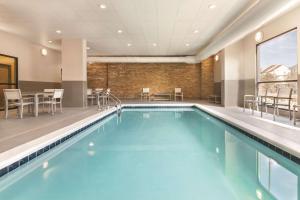 大洋城Country Inn & Suites by Radisson Ocean City的游泳池位于酒店客房内,配有椅子和桌子
