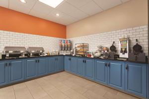 大急流城大急流城东部卡尔森乡村套房酒店的一间设有蓝色橱柜和橙色墙壁的大厨房