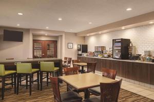 WillmarCountry Inn & Suites by Radisson, Willmar, MN的一间带桌椅的餐厅和一间酒吧