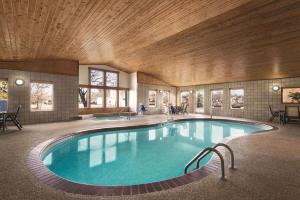 诺斯菲尔德明尼苏达州诺思菲尔德雷迪森乡村套房酒店的一座大型游泳池,位于一座拥有木制天花板的建筑中