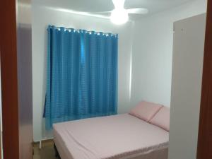 伊列乌斯Apartamento 3/4, 1 suíte Vog Atlântico的一间卧室配有床和蓝色窗帘