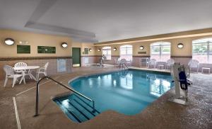 康科德卡尔森康科德/坎纳乡村酒店套房 的游泳池位于酒店客房内,配有椅子和桌子