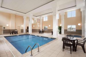 贝德福德曼彻斯特机场乡村套房酒店的一个带桌椅的大房间的一个游泳池