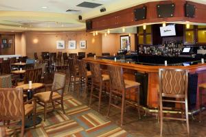 皇后区Radisson Hotel JFK Airport的餐厅内的酒吧配有桌椅