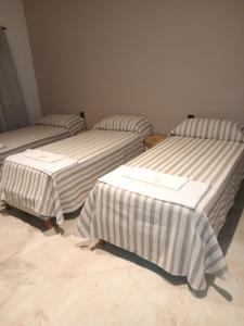 科洛尼亚卡罗亚casa de campo, Bodega Di Candi的带条纹床单的客房内的三张床