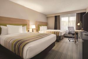 伊利Country Inn & Suites by Radisson, Erie, PA的酒店客房配有两张床和一张书桌