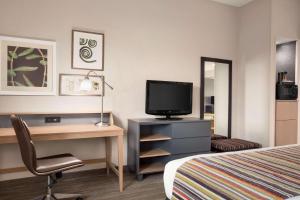 佛罗伦萨佛罗伦萨江山旅馆的酒店客房配有一张床、一张书桌和一台电视。