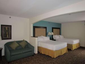 默特尔比奇Country Inn & Suites by Radisson, Murrells Inlet, SC的酒店客房,设有两张床和一张绿色沙发