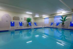 恩波里亚安珀瑞亚乡村套房假日酒店的大楼内带蓝色椅子的大型游泳池