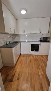 哥德堡Mysigt Stadsoas: En Modern lägenhet med 2 sovrum的厨房铺有木地板,配有白色橱柜。
