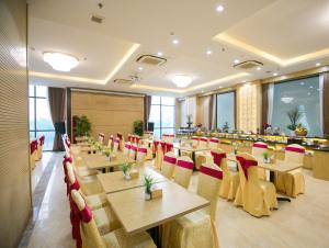 岘港Lavencos Hotel Da Nang的餐厅设有木桌和红色椅子