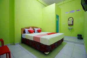 LubuklinggauOYO 2585 Sherren Guest House的一间卧室配有一张带绿色墙壁和红色枕头的床
