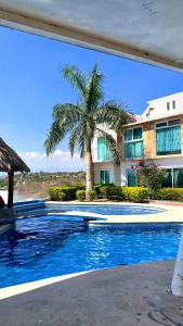 特克塞丁戈casa con hermosa vista al lago de tequesquitengo的棕榈树,在一座带游泳池的房子前