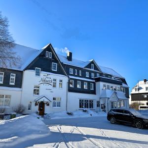 温特贝格Hotel Nuhnetal的雪中酒店,门前有车
