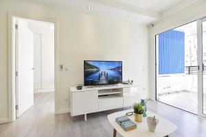 英格兰海滩Modern Iguazu Apartment的白色的客厅配有白色橱柜上的平面电视