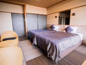 京丹后市LiVEMAX RESORT Kyotango Sea Front的一间卧室配有一张大床和一把椅子