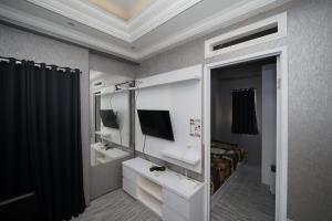 万隆Perfect Stay Apartement The Suites Metro Bandung By Sultan Property的一间带镜子、一张床和电视的卧室