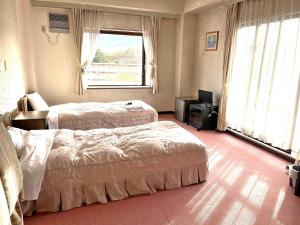 阿扎格瓦セミナープラザ　ロイヤルフジ的一间卧室设有两张床、一台电视和一扇窗户。