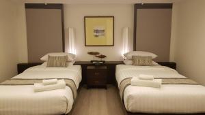清迈清迈兰特瑞酒店的一间卧室配有两张带白色床单的床