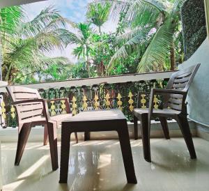 巴加Hotel Adam's Baga Beach Resort Goa - 2 minutes walk from Baga Beach的棕榈树阳台的两把椅子和一张桌子