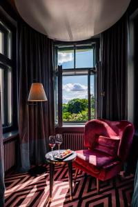 里加Grand Poet Hotel and SPA by Semarah的一间设有红色椅子、桌子和窗户的房间