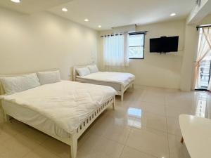 高雄蔚宿佳塩的一间卧室设有两张床,墙上配有电视。