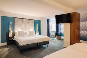 阿姆斯特丹Eden Hotel Amsterdam的酒店客房设有两张床和电视。