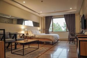 伊斯兰堡Roomy Signature Hotel, Islamabad的酒店客房配有床、沙发和桌子。