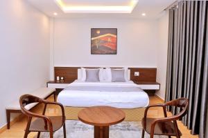 海防An Tín Hotel的酒店客房带一张床、一张桌子和椅子