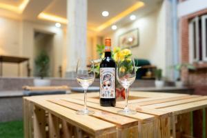 帕坦Nyadha House Bed & Breakfast的木桌旁的一瓶葡萄酒和两杯酒