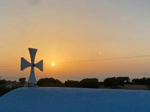 塞奥洛戈斯Summer View的屋顶上的十字架,背面是日落