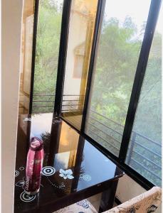 纳西克Aashiyana的一间设有桌子的房间和窗户,窗户上装有一瓶酒