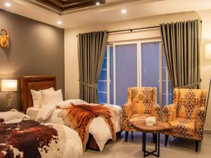 穆里The Roomy Lodge, Murree的酒店客房带两张床、椅子和窗户