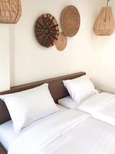 清迈บ้านสวนอินทาวน์ Baansuan in Town Hotel的两张带白色枕头和墙上篮子的床