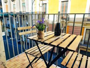 卡塔尼亚DUHOME apartment in the heart of Catania的阳台上的木桌,摆放着鲜花和玻璃杯