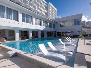 圣胡安Hilton Garden Inn San Juan Condado的一座带白色椅子的游泳池