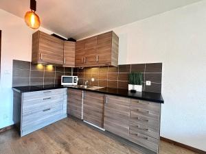 克松吕-隆日梅Studio La Belle Vue的一间带木制橱柜和微波炉的厨房