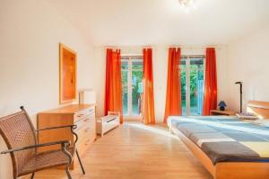 霍恩维舍多夫Strandhaus Fiete - Haus Poelblick - ABC247的一间卧室配有橙色窗帘、一张床和椅子