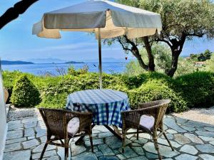 梅加利阿莫斯Villa Athena Skiathos的露台的遮阳伞下的桌椅