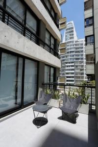 布宜诺斯艾利斯OWN Belgrano Studios & Suites的大楼内的阳台配有两把椅子和一张桌子