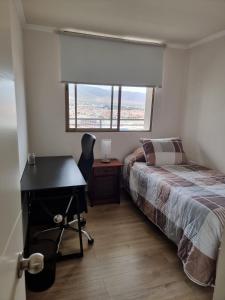 安托法加斯塔El Faro Antofagasta的一间卧室配有书桌和一张带窗户的床