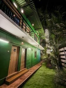 曼德姆Seaside Serenity Resort的一座绿色墙壁的建筑和一条带草地的走廊