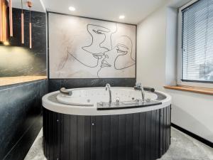 格丁尼亚JACUZZI A&J APARTS GDYNIA的浴室配有壁画和浴缸