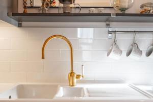 梅尔罗斯Bijou apartment in the heart of Melrose的厨房水槽配有金色水龙头和3个计量杯子