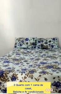 盖比姆Casa p/ temporada, praia guaibim的一张床上有蓝色花卉,上面有标志