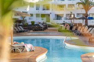 科斯塔特吉塞加里昂海滩公寓的酒店旁的游泳池配有桌椅